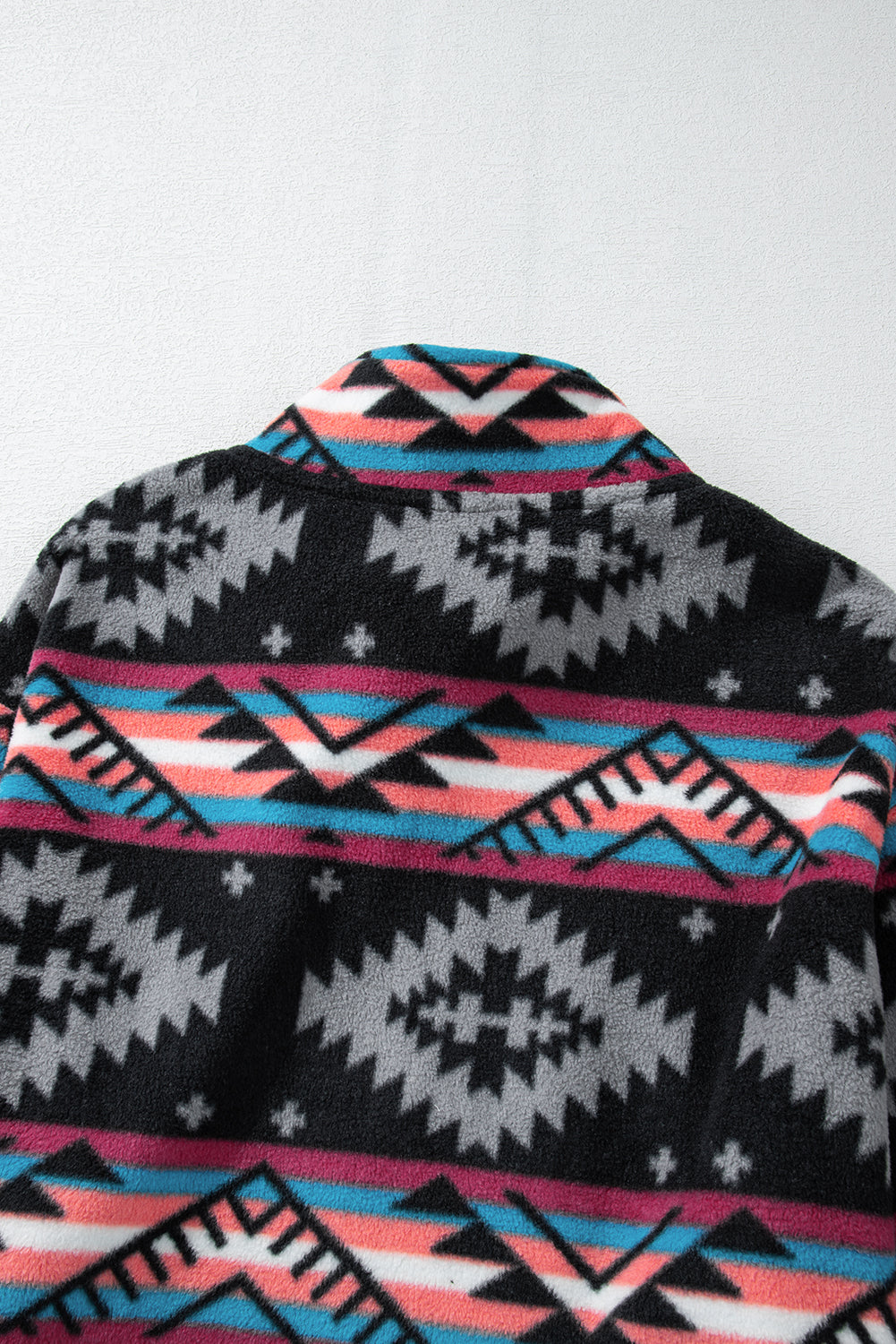 flat lay of Aztec print zip up jacket in black and grey. Close up back view